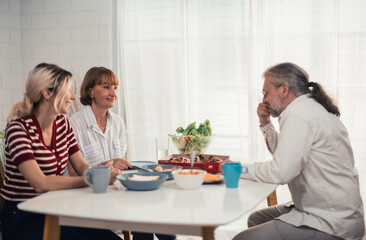 Members of the family from multiple generations enjoy quality time together by eating, snacking,...
