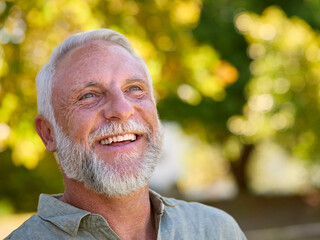 Portrait Of Smiling Senior Man Standing Outdoors In Garden Park Or Countryside