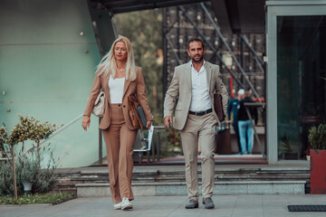 Obraz premium Modern business couple after a long day's work, walking together towards the comfort of their home, embodying the perfect blend of professional success and personal contentment.