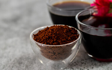 Close up shot of coffee powder in glass bowl with defocused black coffee.