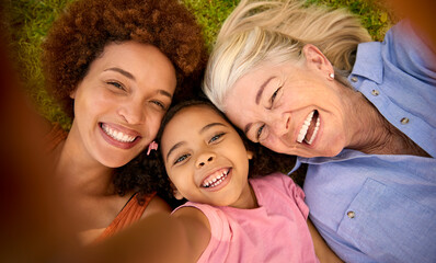 POV Overhead Shot Of Multi-Generation Female Family Lying On Grass Taking Selfie On Mobile Phone