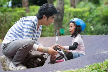 Father or a trainer talks to 4 years old little girl about a bike riding mistake at the pump track, kids with outdoor sports