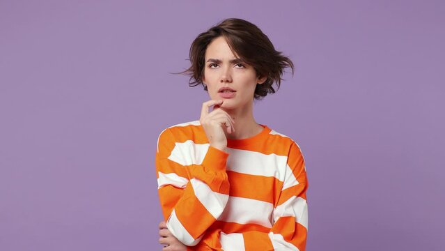 Puzzled young woman wear casual clothes look aside put hand prop up on chin iterates over solution options feels doubtful thinks but no decision comes isolated on plain pastel light purple background