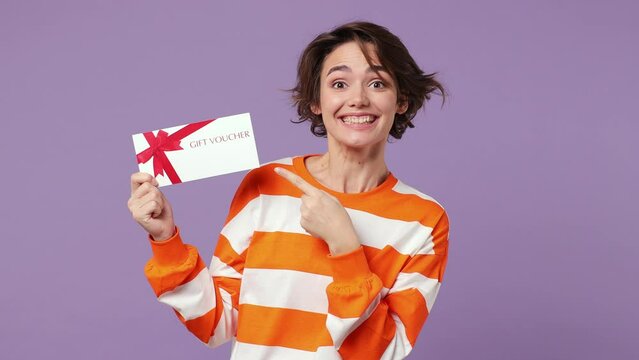Surprised shocked happy young caucasian woman wear casual clothes pointing finger on gift certificate coupon voucher card for store do winner gesture isolated on plain pastel light purple background