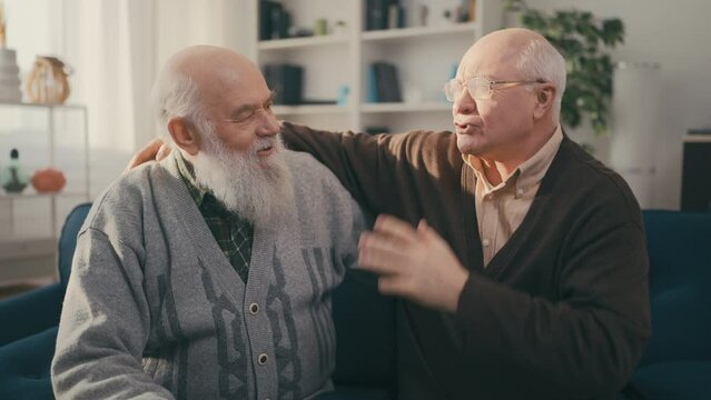 Two elderly men bumping fists, friends communicating at home, male friendship