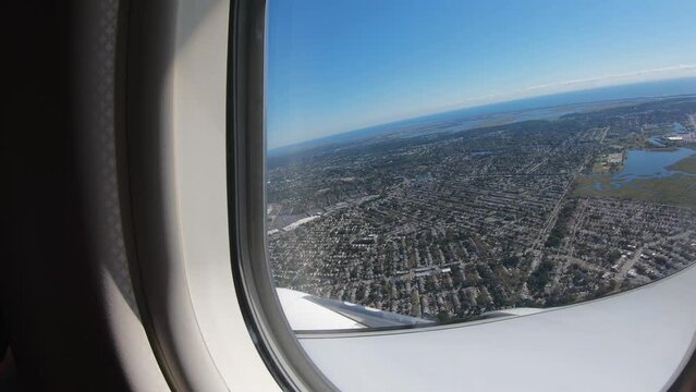 Plane taking off from JFK airport. Place window view of the Atlantic Ocean and New York suburb