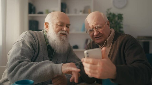 Senior men figuring out how to use a smartphone, digital era, modern technology