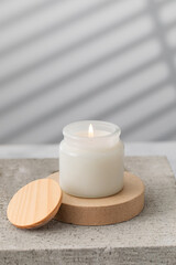Fototapeta na wymiar A burning white interior candle in a glass cup. The concept of home decor, comfort. Handmade candle