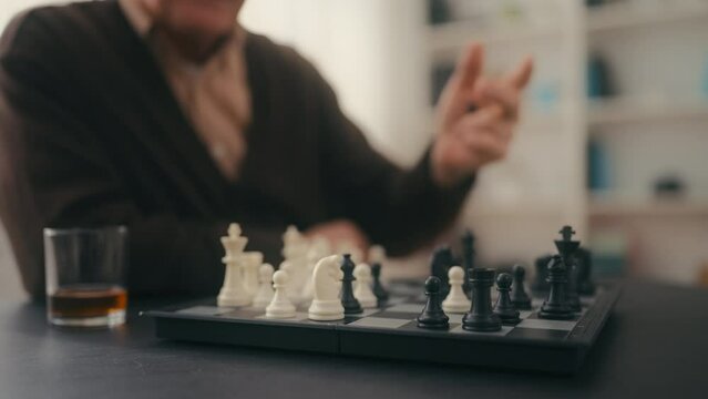 Closeup of elderly man playing chess at home, loneliness, old age, retirement