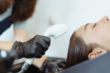 Close up shoot of Asian beautiful woman get hair washing and caring at professional salon shop.