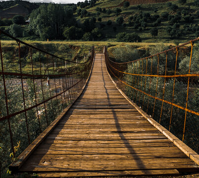 rusty wooden bridge over the river at sunset