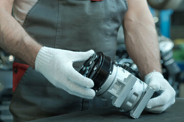 A new compressor for an air conditioner in the hands of an auto mechanic. A car service specialist...