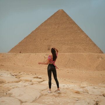 Tall pretty model girl in leather pants standing in front of the Pyramid of Giza