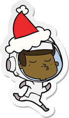 hand drawn sticker cartoon of a confident astronaut wearing santa hat
