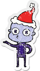 hand drawn distressed sticker cartoon of a weird bald spaceman wearing santa hat