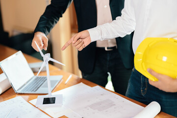Close-up of hands of two Asian male architects, looking like engineers, pointing at a model wind...
