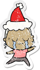 hand drawn distressed sticker cartoon of a crying old lady wearing santa hat