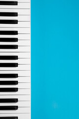 Flat lay background with piano, white synthesizer on blue background, musical keys isolated, top view, copy space.