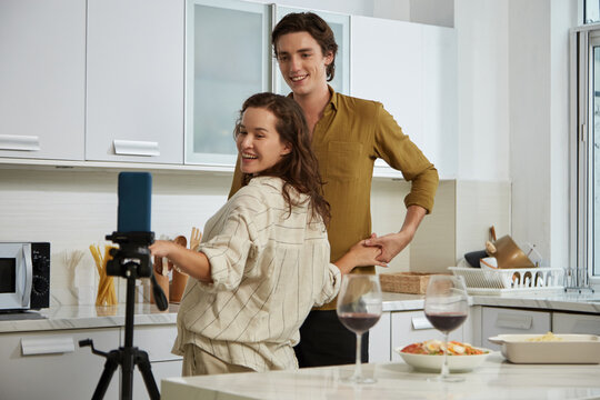 Young couple filming video in kitchen for their blog on social media