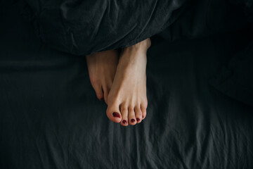 Beautiful feet of a sleeping woman under a blanket