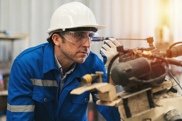 Male engineer worker repair automatic robotic arm in factory. Male technician worker inspecting...