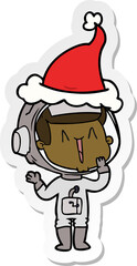 laughing hand drawn sticker cartoon of a astronaut wearing santa hat