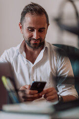 A businessman using on his smartphone while seated in an office, showcasing his professional demeanor and active communication.