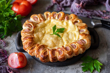 Hearty lunch: sausage and cheese pie on a gray background. Close-up. Cheese pie for dinner for the...