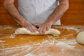 Baker kneading artisan bread in the bakery.