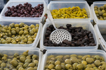 Various sorts of green and black pickled olives in plastic boxes for sale at the market, harvested from an organic farm in Makedonia, Greece, copy space, selected focus