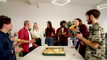 Group of coworkers having fun during office party. Happy friends drink beer and eating pizza