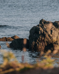 rocks in the sea with waves around at sunset