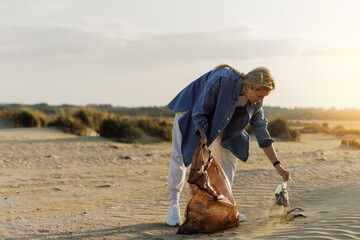 Woman volunteer is collecting plastic waste on the beach to contribute to the effort of keeping nature clean