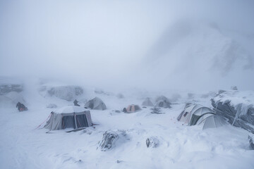 Yellow tents of icy base camp on mount everest covered in fog and snow - Generative AI
