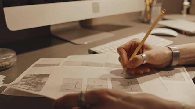 Focus on hands of woman sitting at desk in office writing something on project documents with pencil