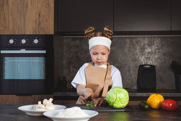 Cooking or Culinary school for children, kids. Little girl cooks on the kitchen, preparing ingredients, cutting vegetables.