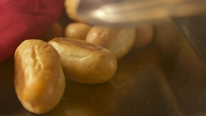 fresh hot pastry on iron tray steam pick it up with a tong red napkin in a restaurant serving food selection delicious crust Grocery white bread breakfast lunch dinner lunch - Powered by Adobe