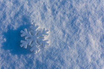 A giant snowflake is lying on the ground covered with snow.