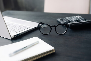 Professional Accounting Setting: Office Desk Featuring Calculator, Laptop, and Glasses - Depicting Finance, Business, and Modern Accountancy Concepts