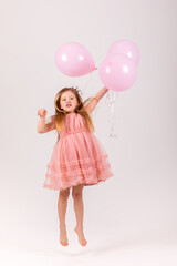 People, joy, fun and happiness concept. Relaxed happy birthday little girl celebrating cheerful, smiling happily, posing for picture, holding colorful helium balloons