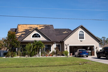 Damaged house roof with missing shingles after hurricane Ian in Florida. Consequences of natural...