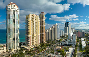 Expensive highrise hotels and condos on Atlantic ocean shore in Sunny Isles Beach city and busy street traffic. American tourism infrastructure in southern Florida