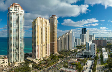 Obraz premium Expensive highrise hotels and condos on Atlantic ocean shore in Sunny Isles Beach city and busy street traffic. American tourism infrastructure in southern Florida