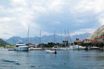 Fototapeta na wymiar Ancient town Kotor by Bay of Kotor (Boka), Montenegro. Boats on water by coast.