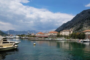 Fototapeta na wymiar Ancient town Kotor by Bay of Kotor (Boka), Montenegro. Boats on water by coast.