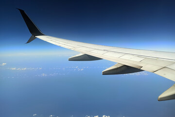 View through airplane window of commercial jet plane wing flying high in the sky. Air travelling concept