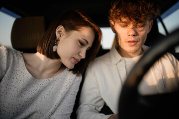 couple in love in a car look at a smartphone choose a travel route, use the application