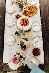 top view of the served table with snacks. decorated table with white tablecloth and plates	
