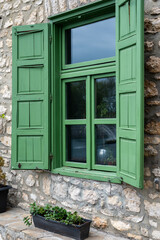 Fototapeta na wymiar Green wooden shutters of an old cottage. protects the windows close with double doors