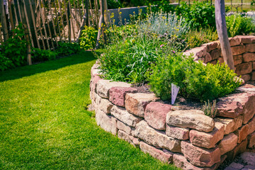 Herb spiral made of bricks for a small garden with green lawn